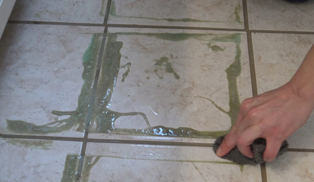 Close-up of white bubbles and foam reacting with dirty grout lines on a ceramic tile floor.